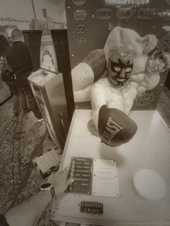 Antique arm-wrestling arcade machine wearing a luchador mask