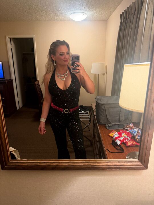 Night Shade taking a mirror selfie in a hotel room wearing a black sequinned halter outfit