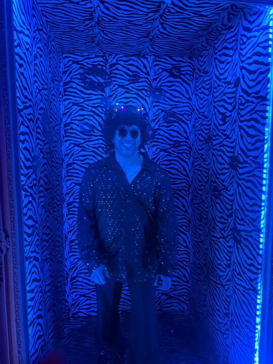 Commander standing in a zebra-print photo corridor lit deep blue