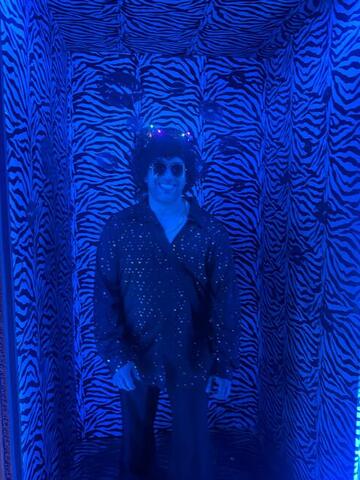 Commander standing in a zebra-print photo corridor lit deep blue