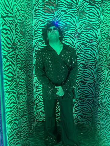Commander standing with hands clasped in a zebra-print photo corridor lit green