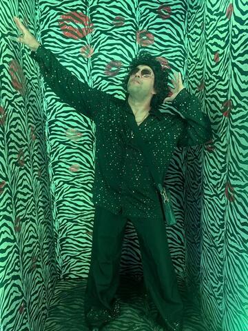 Commander with arms spread wide against a green-lit zebra-print wall