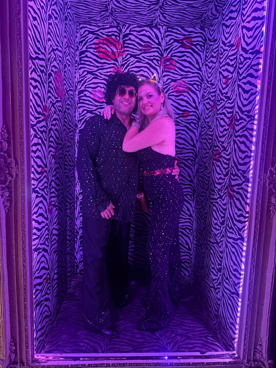 Commander and Night Shade posing together in a violet-lit zebra-print photo corridor