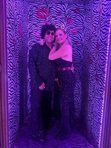 Commander and Night Shade posing together in a violet-lit zebra-print photo corridor