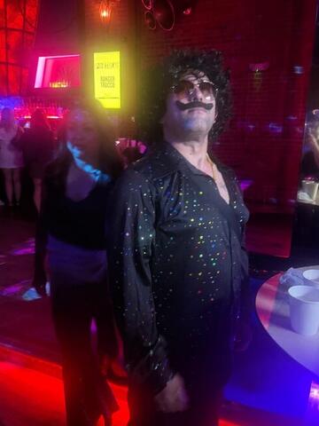 Commander standing near a mirror ball in a dark red-lit club