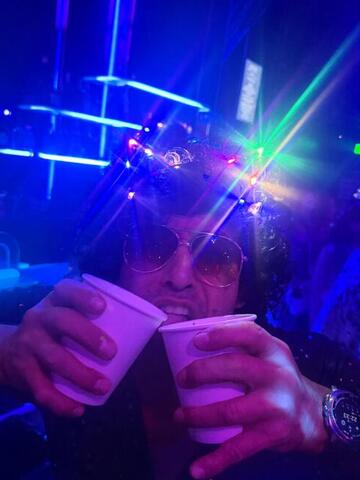 Two cups held up under blue laser beams in a dark club