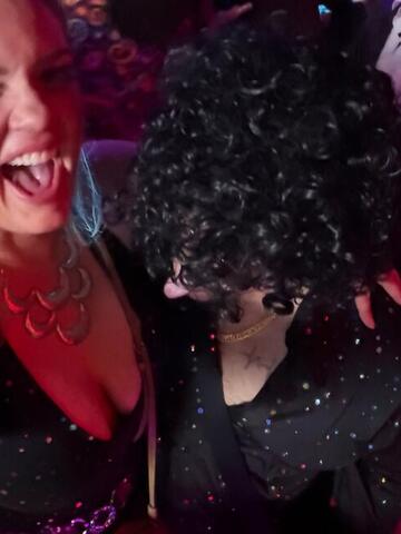 Night Shade laughing beside the back of the Commander's curly black wig