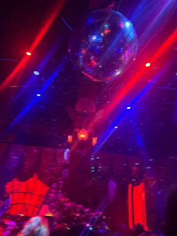 A mirror ball catching red and blue light in a dark club ceiling