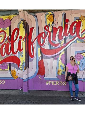Night Shade standing in front of a colourful California mural at Pier 39