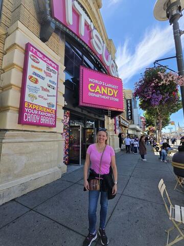Night Shade standing on a sunny street outside a large candy store