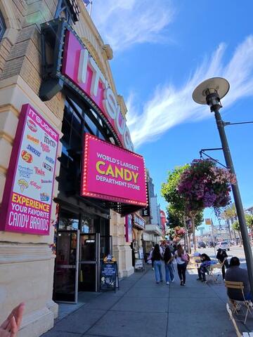 The bright pink and yellow facade of a large candy store on a sunny street