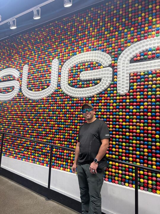 Commander standing in front of a huge multicoloured wall of candy