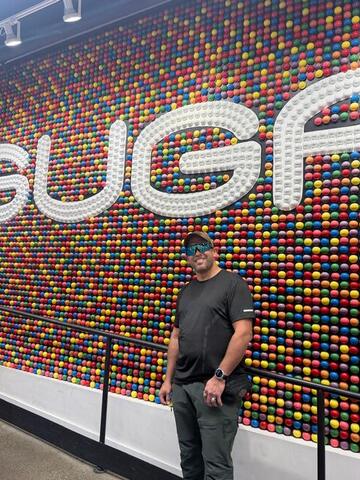 Commander standing in front of a huge multicoloured wall of candy