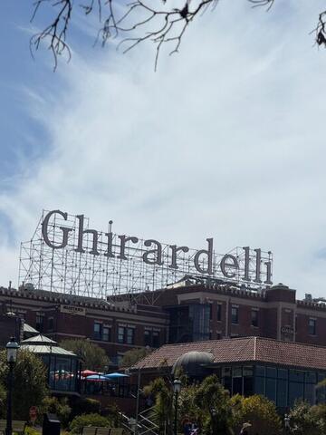 The large rooftop Ghirardelli sign seen through bare branches